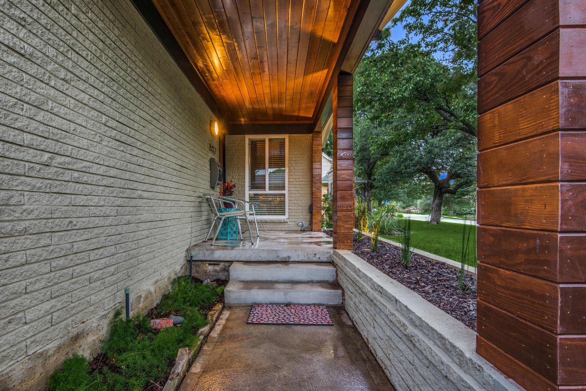 A brick house remodel with a porch and stairs leading up to it.