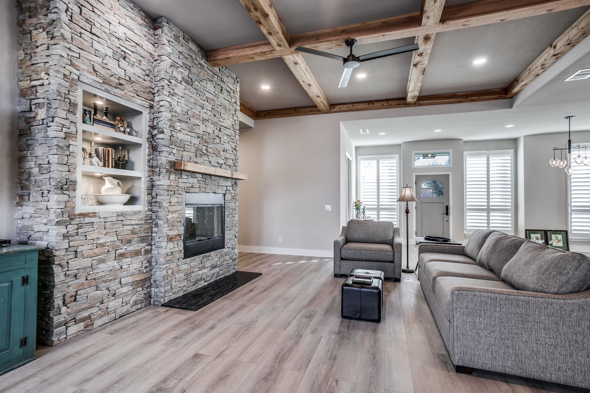 A living room with a couch , chair , fireplace and wooden beams.