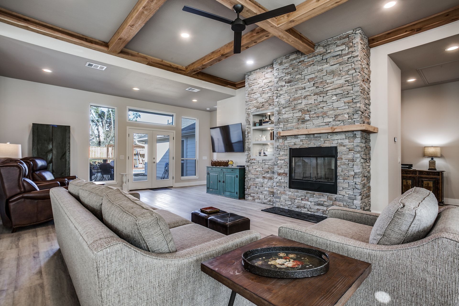 A living room with a couch , chairs , a fireplace and a ceiling fan.