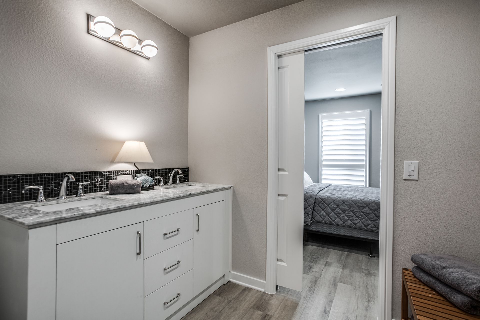 A bathroom with a sink and a door leading to a bedroom.