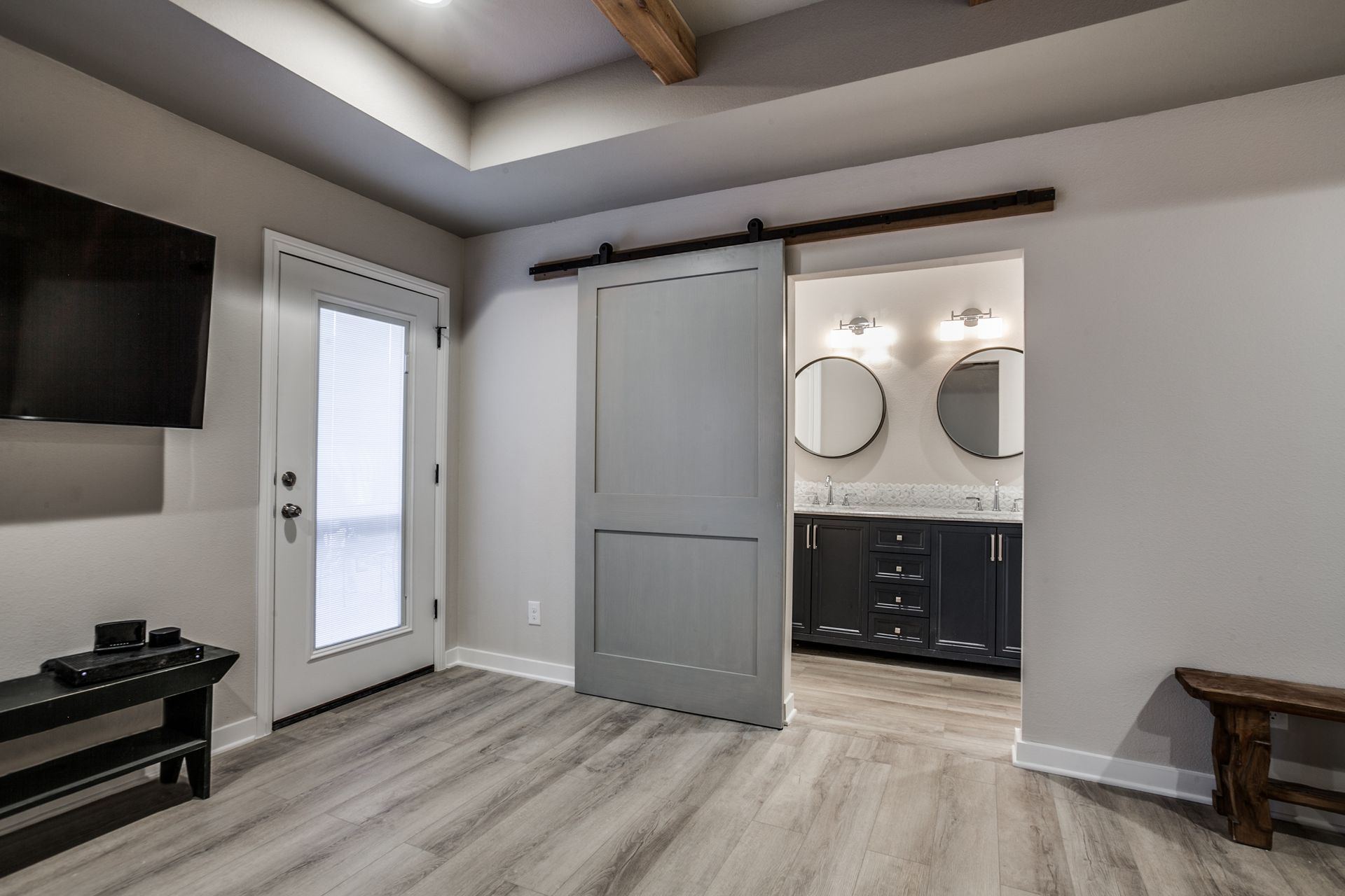 A living room with a sliding barn door leading to a bathroom.