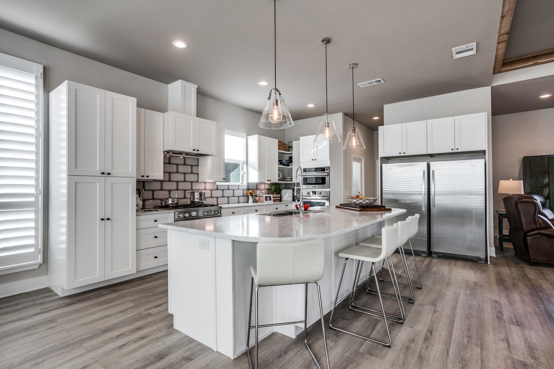 A kitchen with white cabinets , stainless steel appliances , and a large island.