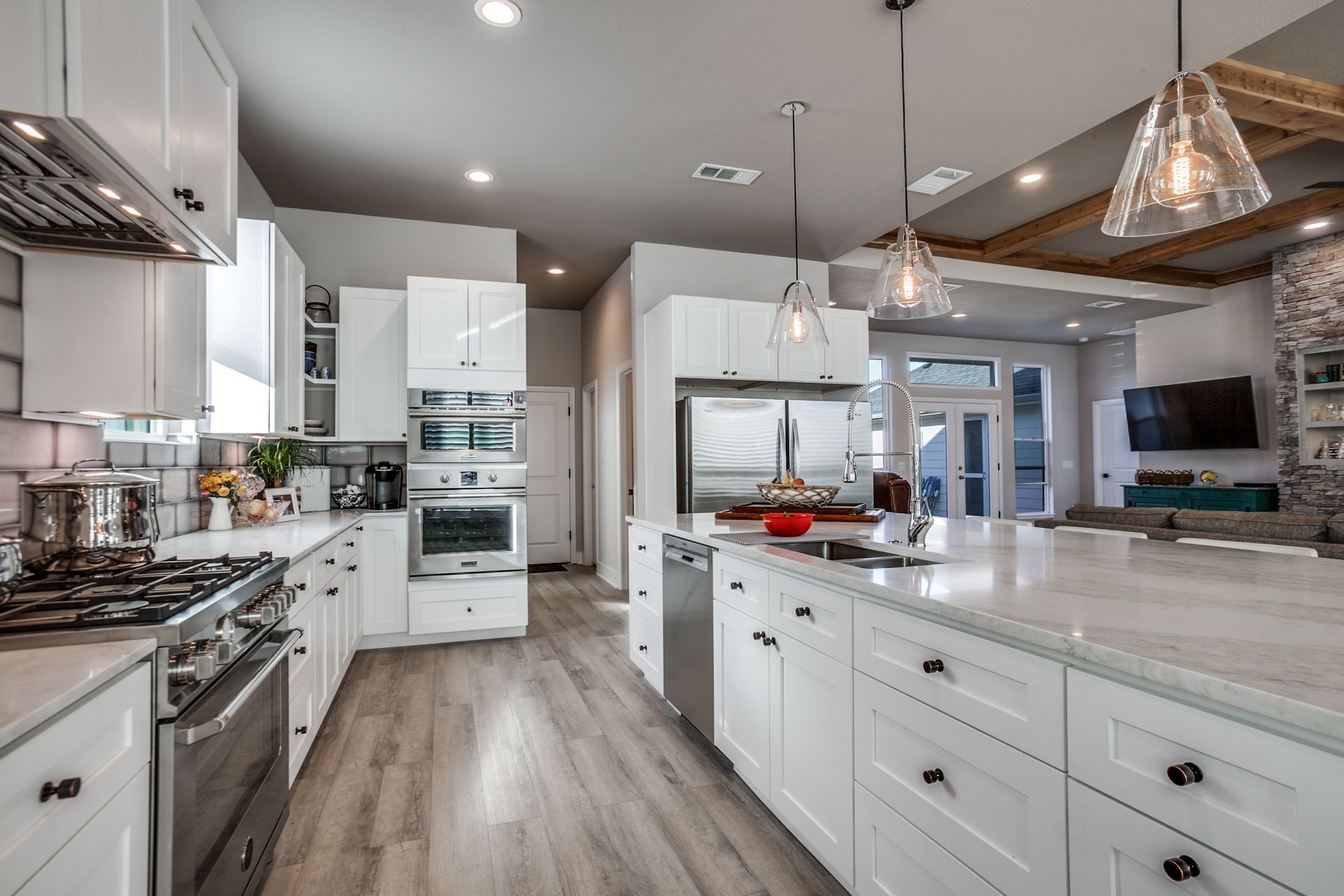 A kitchen with white cabinets , stainless steel appliances , and a large island.