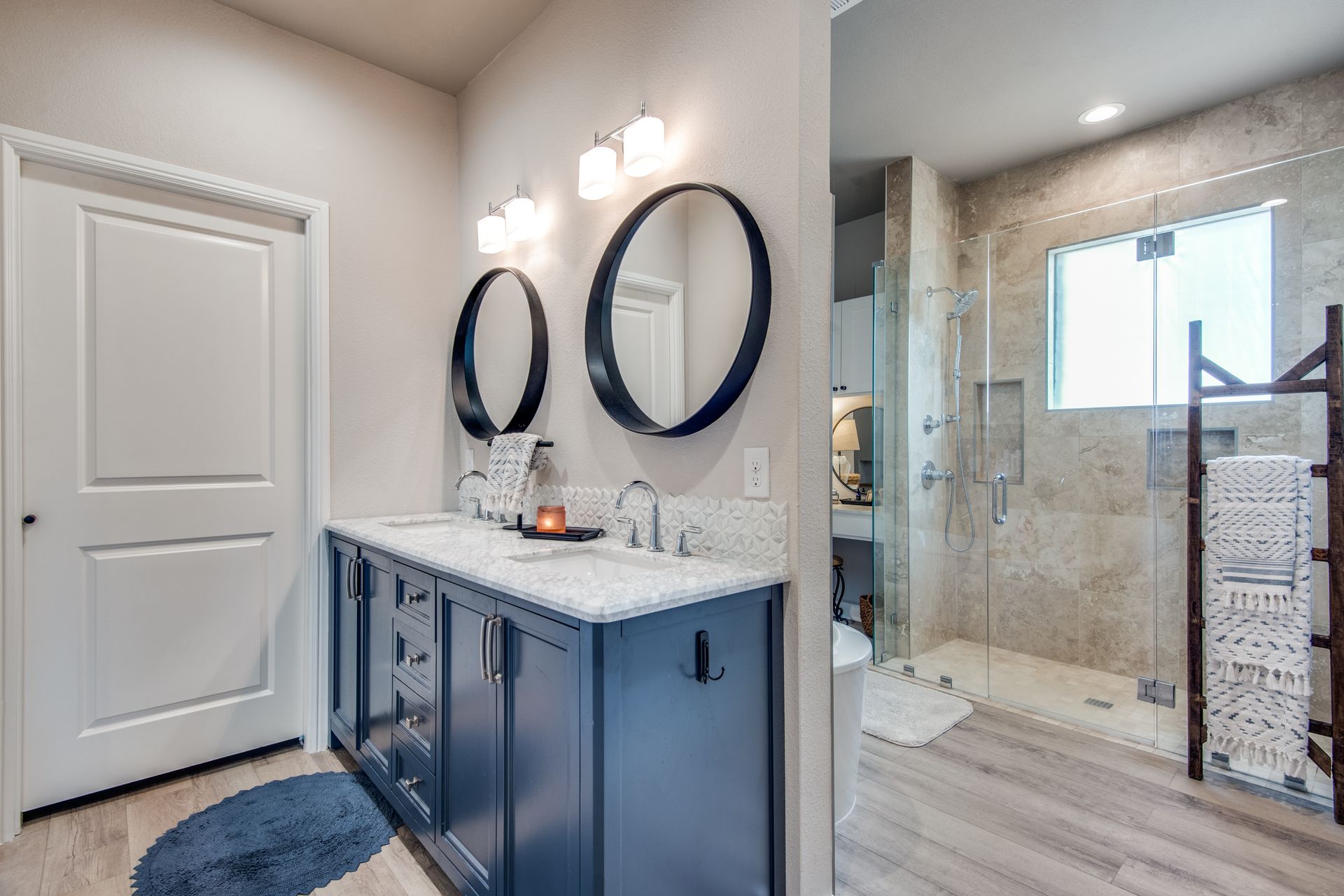 A bathroom with two sinks , two mirrors and a walk in shower.