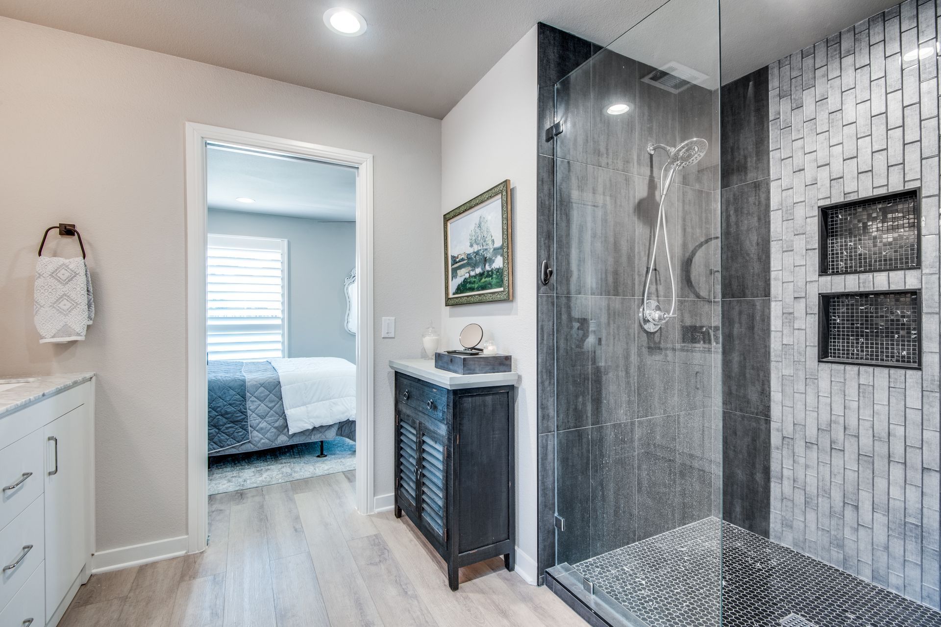 A bathroom with a walk in shower and a vanity.