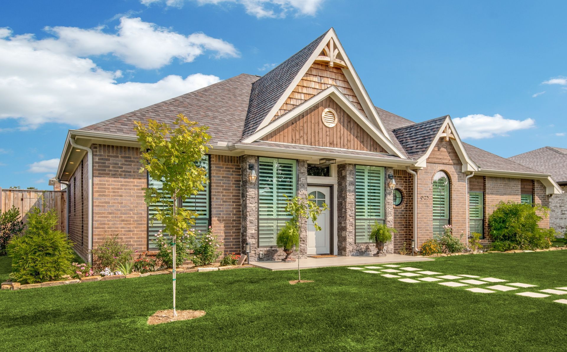 A large brick house remodel with a lush green lawn in front of it.