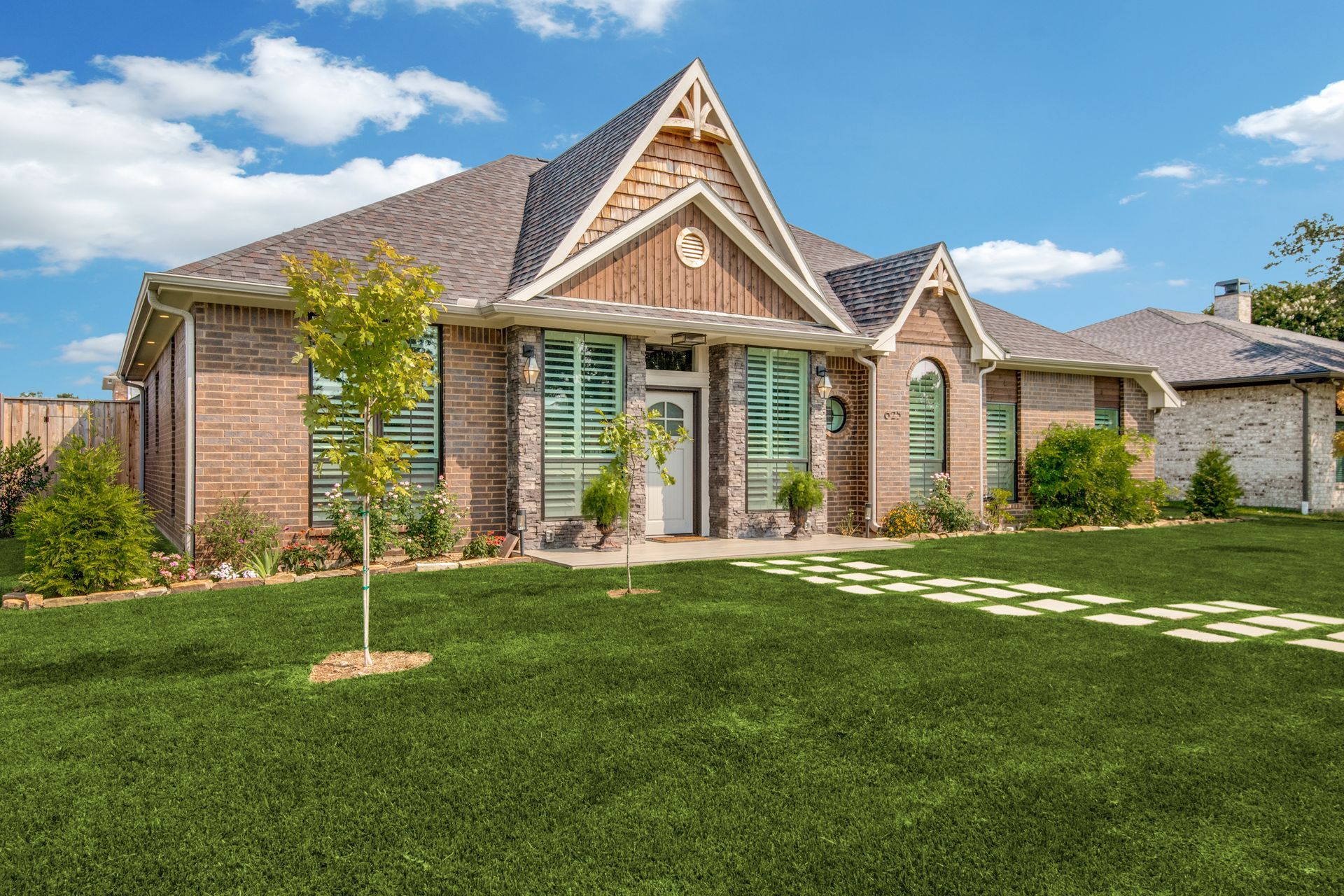 A large brick house remodel with a lush green lawn in front of it.