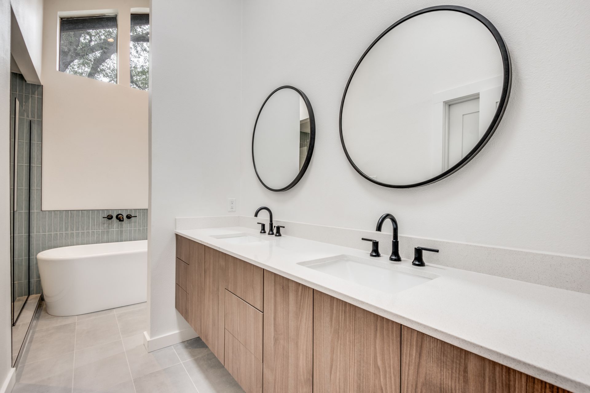 A bathroom with two sinks , two mirrors and a bathtub.