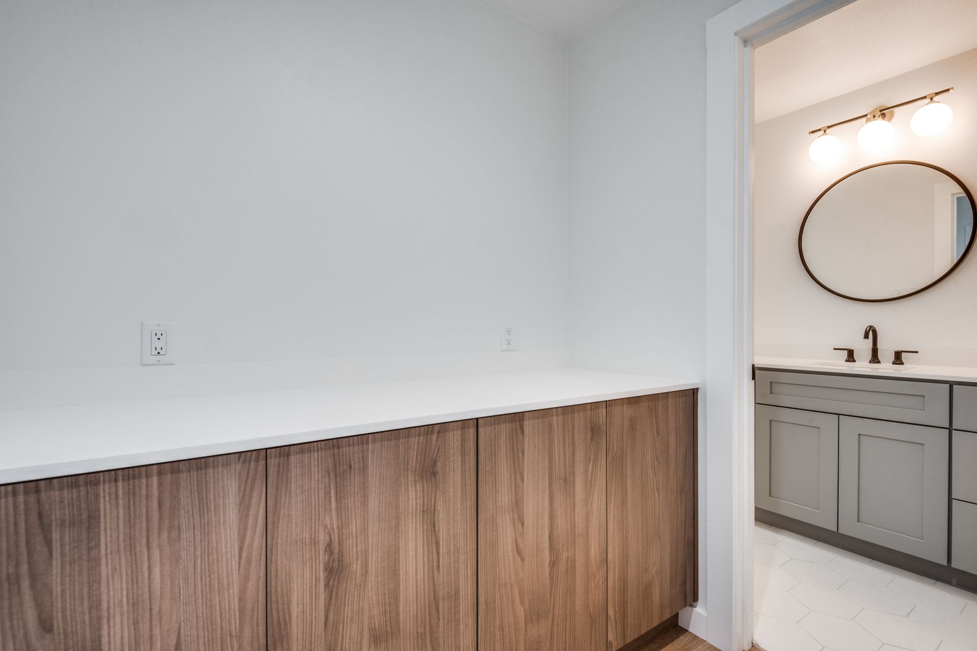 A bathroom with a sink , mirror and wooden cabinets.