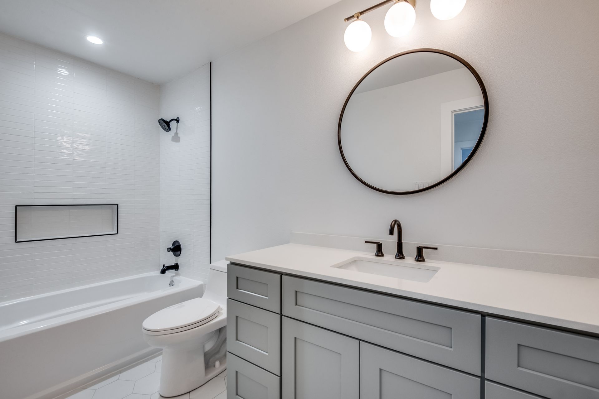 A bathroom with a toilet , sink , bathtub and mirror.