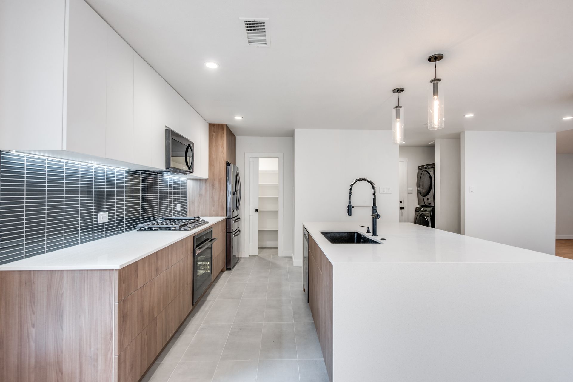 A kitchen with white counter tops , wooden cabinets , stainless steel appliances and a large island.