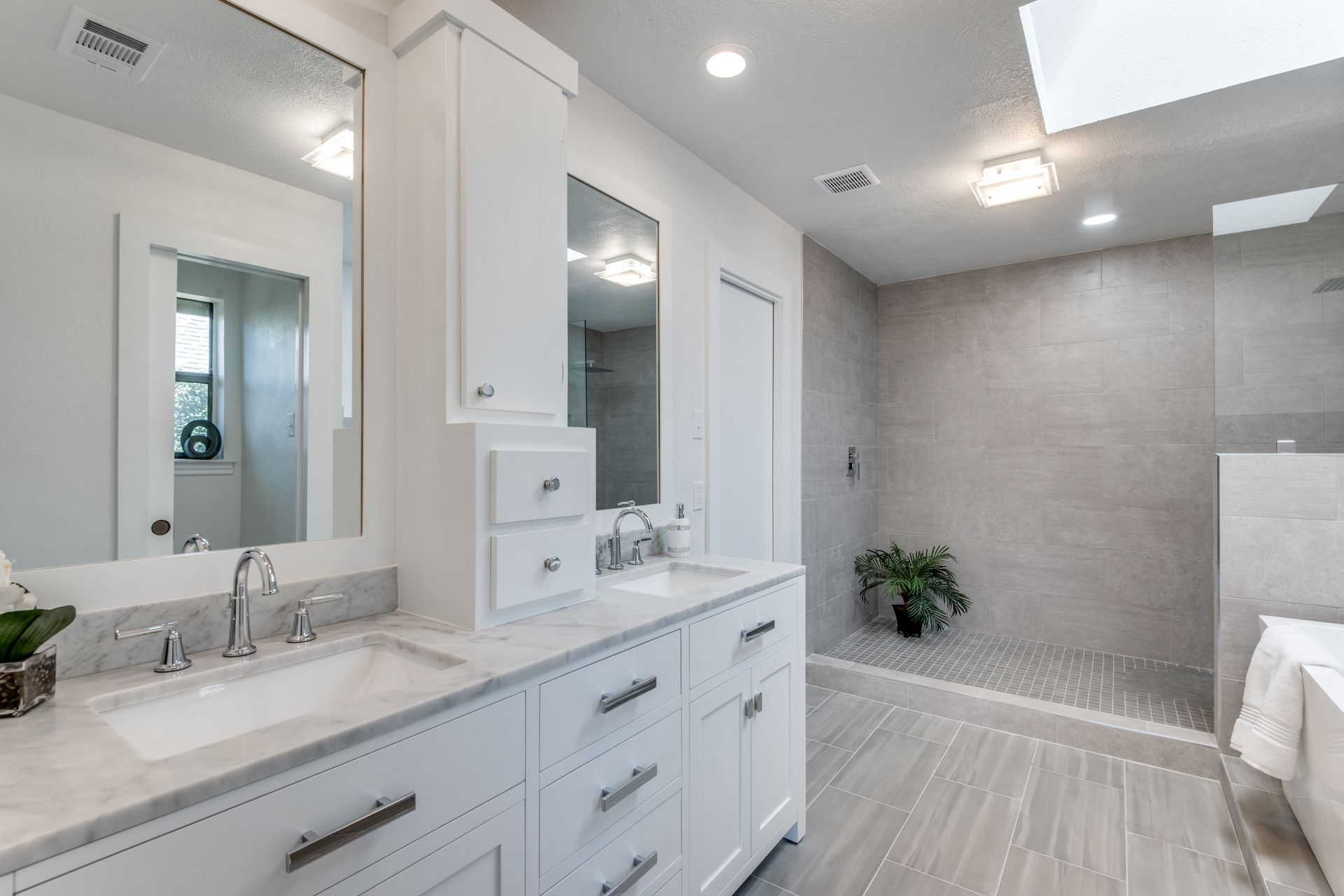 A bathroom remodel with two sinks , two mirrors and a walk in shower.