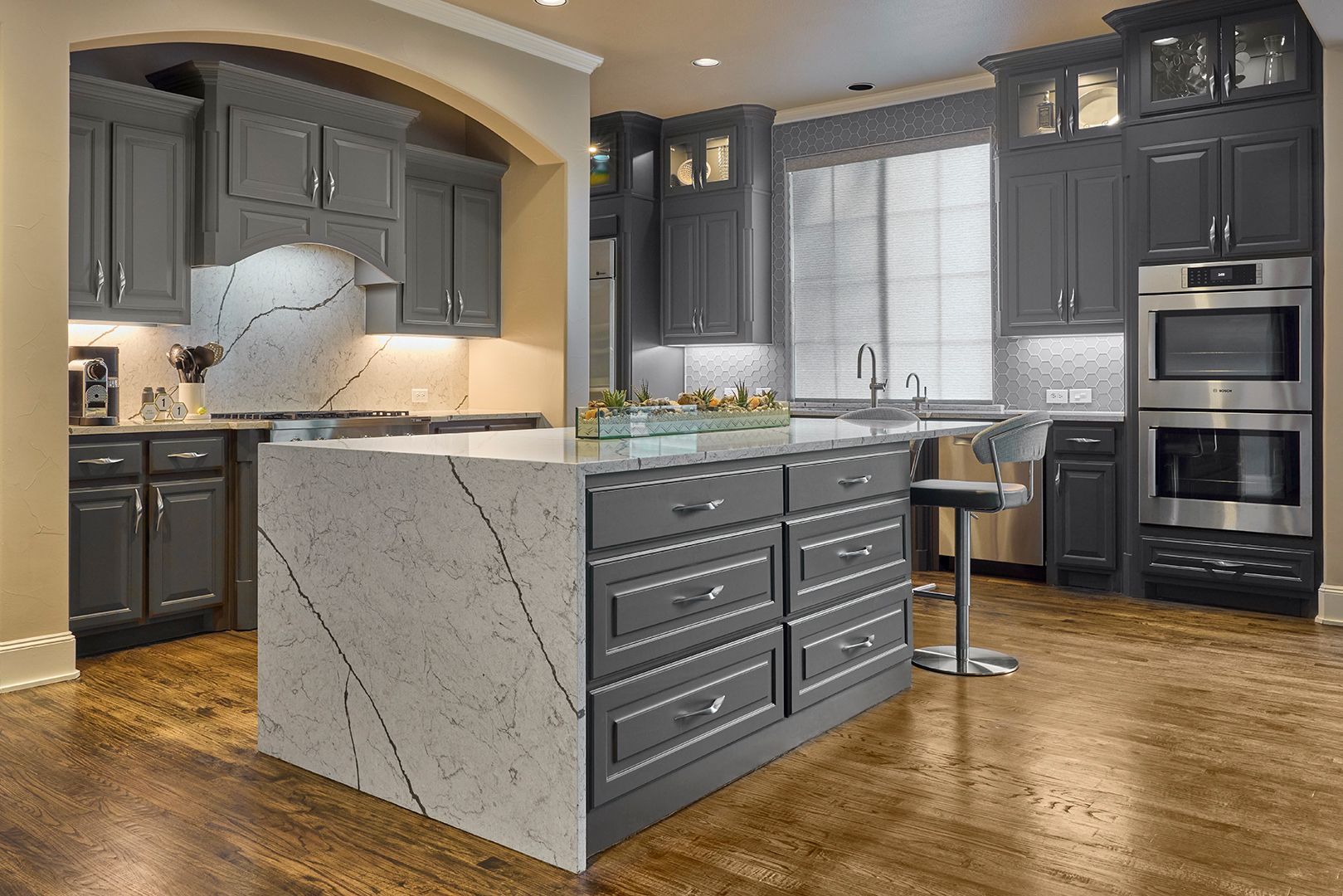 A kitchen with gray cabinets and a large island in the middle.