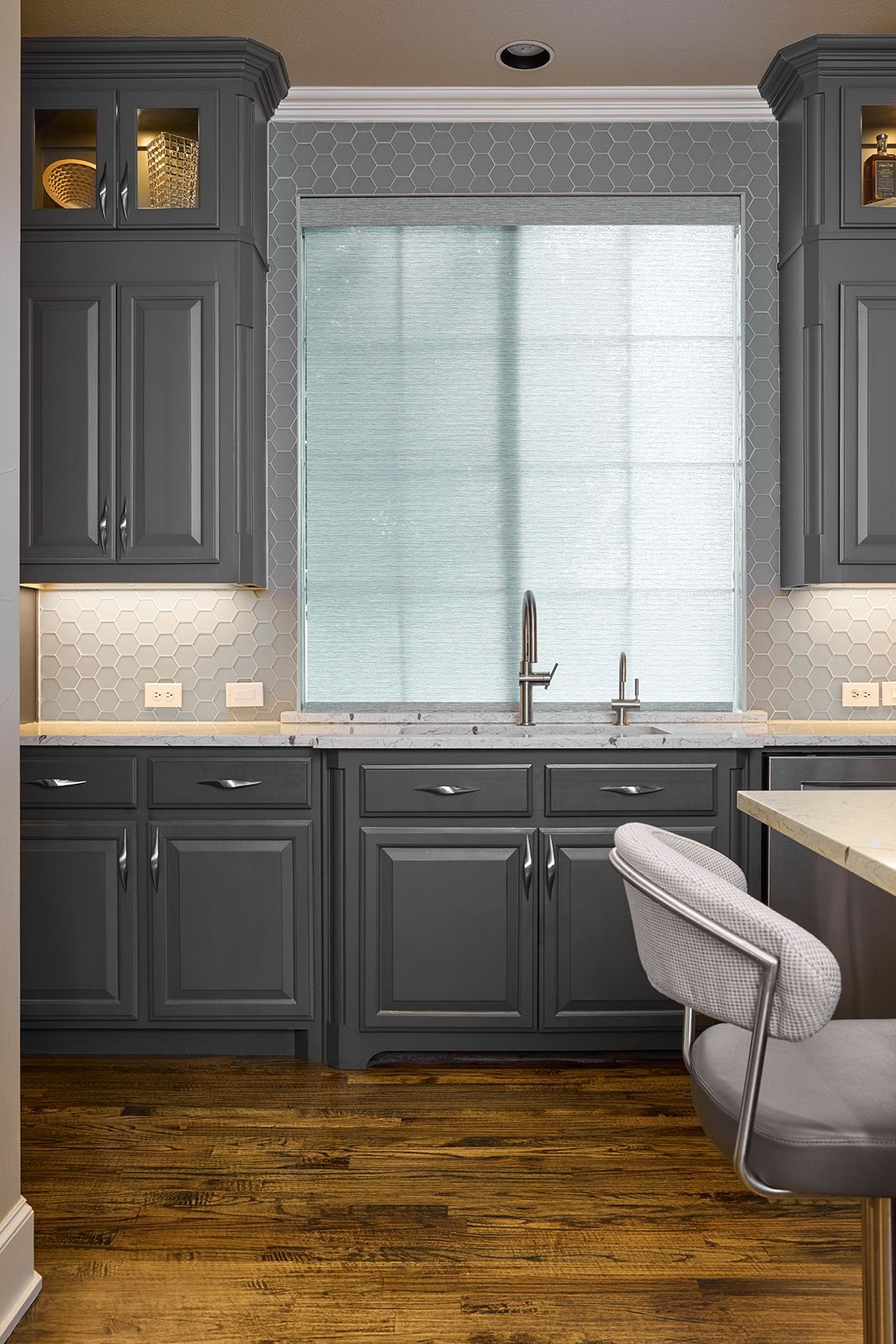 A kitchen with gray cabinets , a sink , and a window.