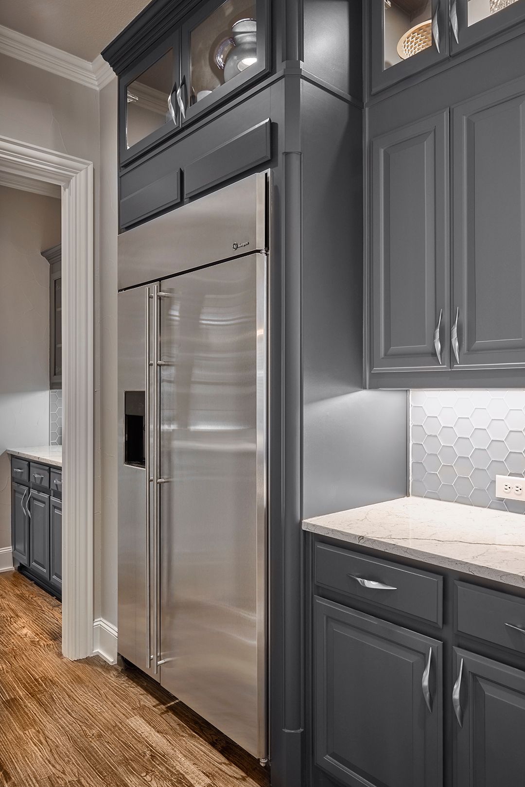 A kitchen with gray cabinets and a stainless steel refrigerator.