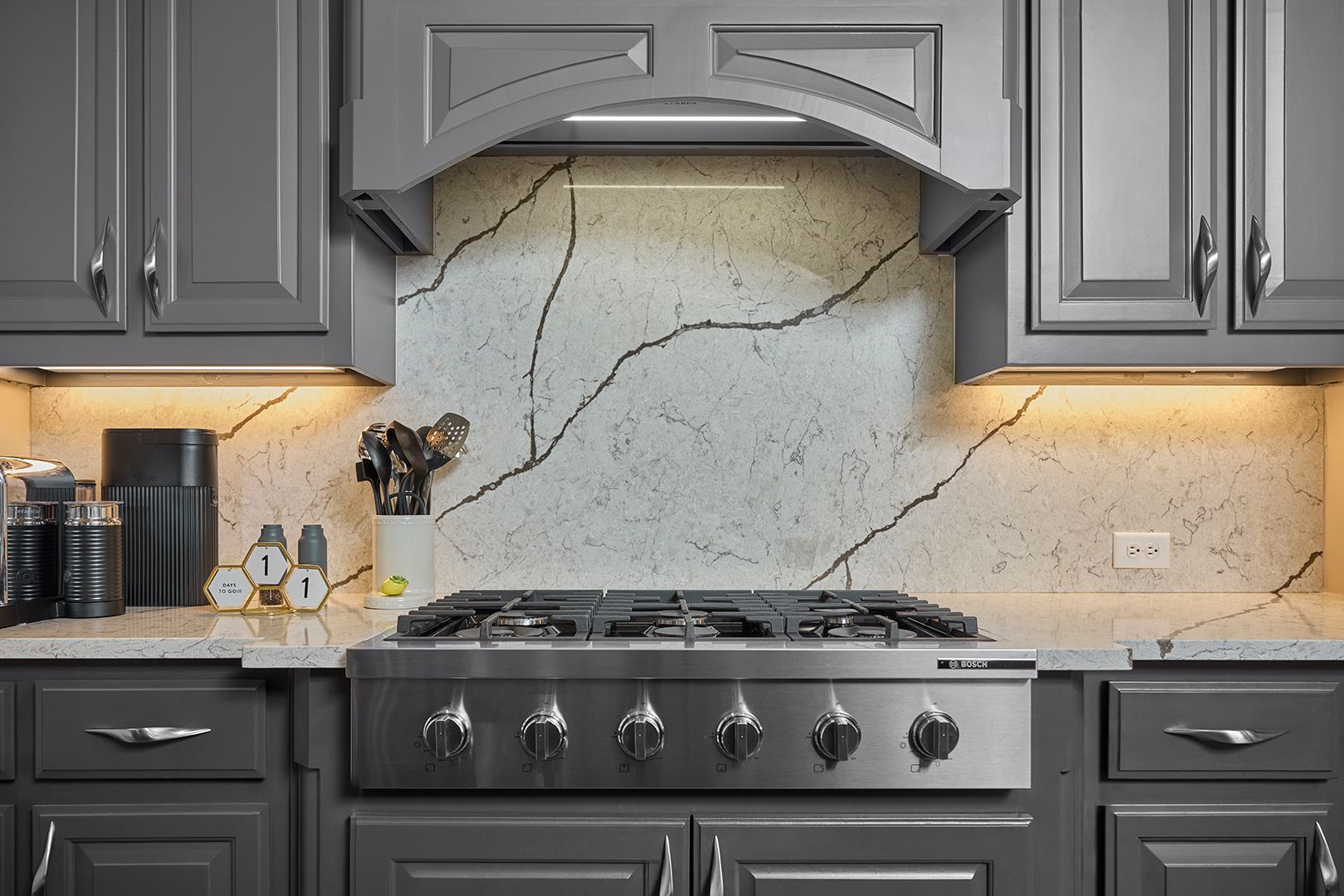 A kitchen with gray cabinets and a stove top oven.