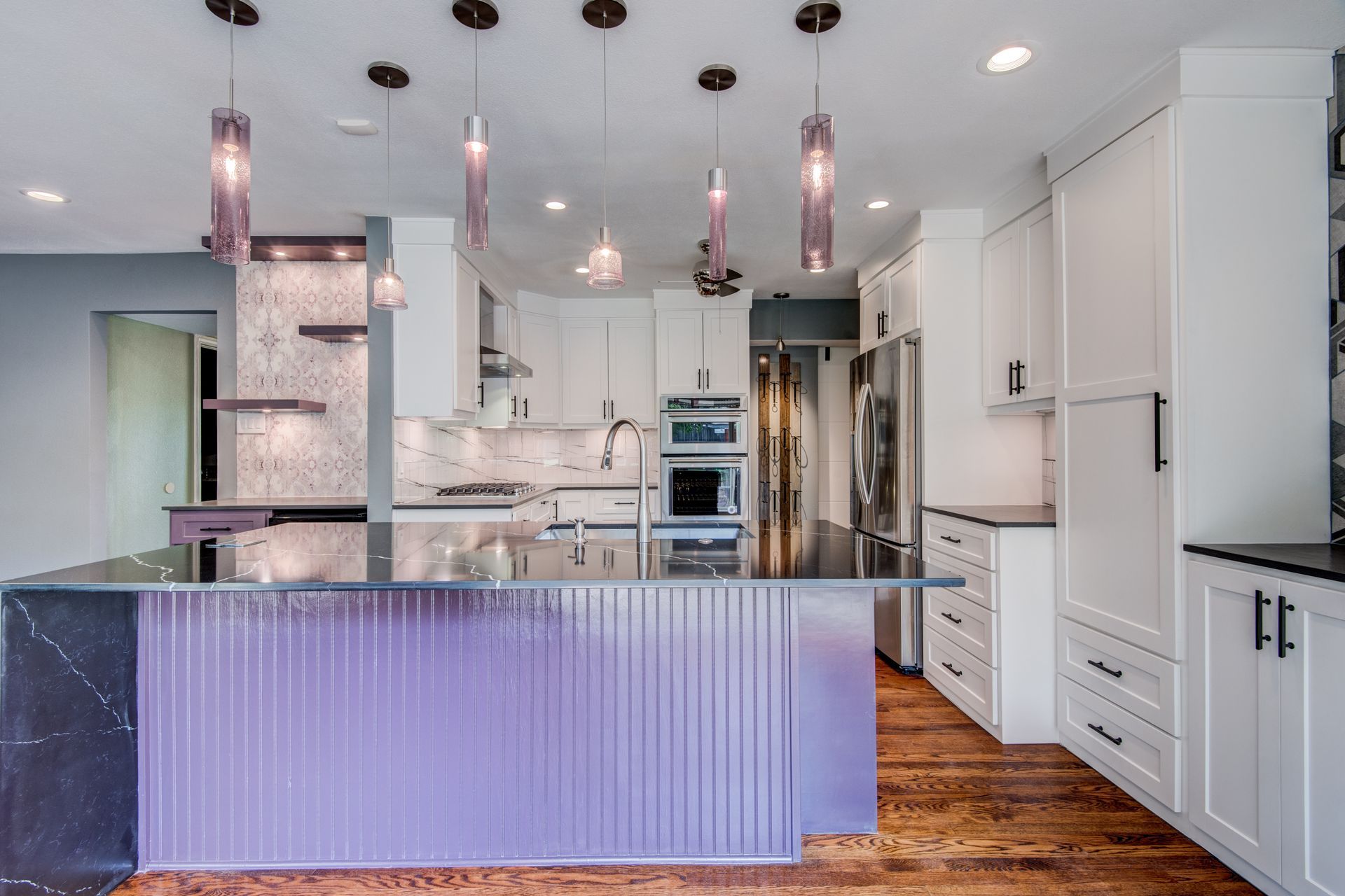 A kitchen with purple counter tops , white cabinets , and stainless steel appliances.