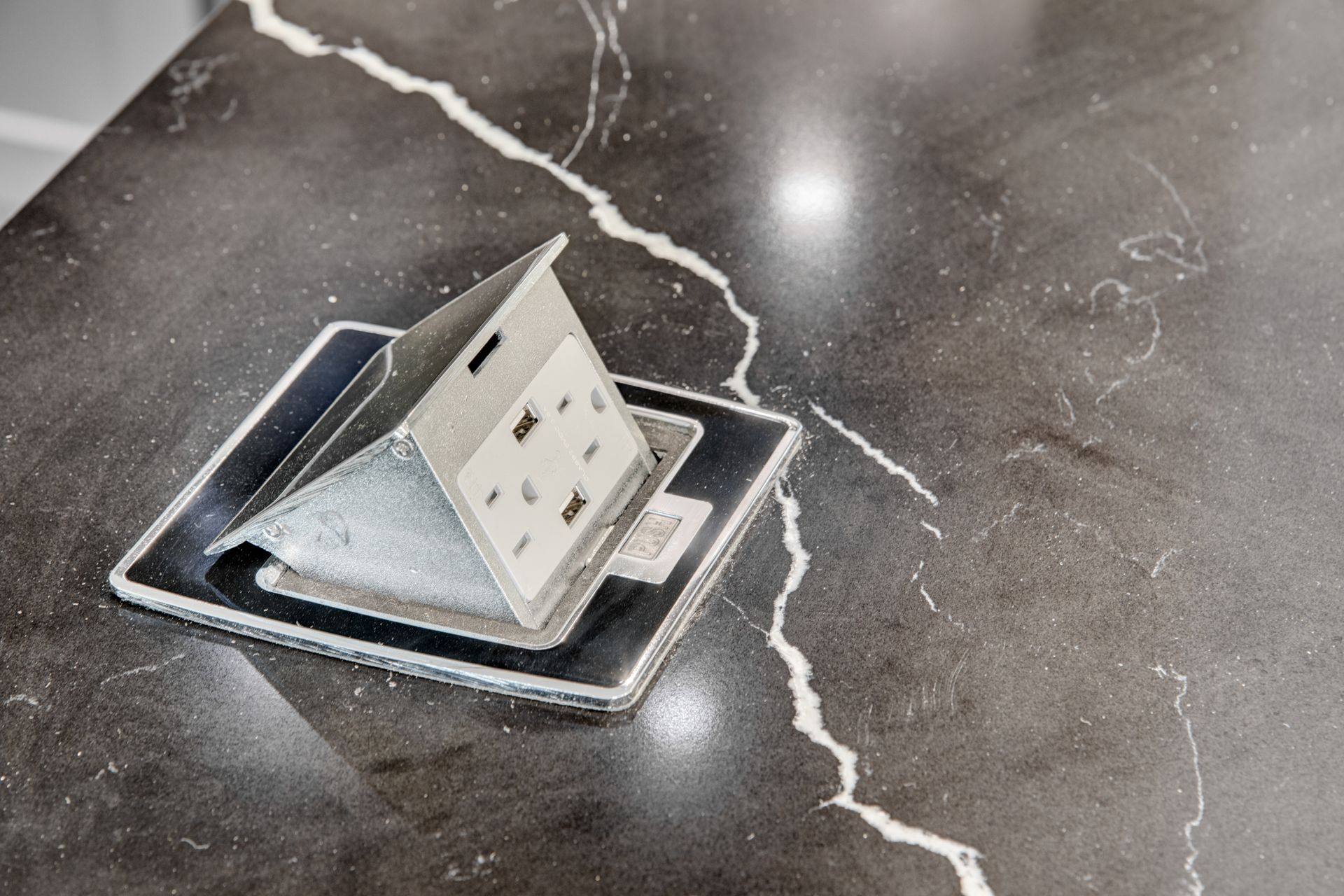 A power outlet is sitting on top of a marble counter top.