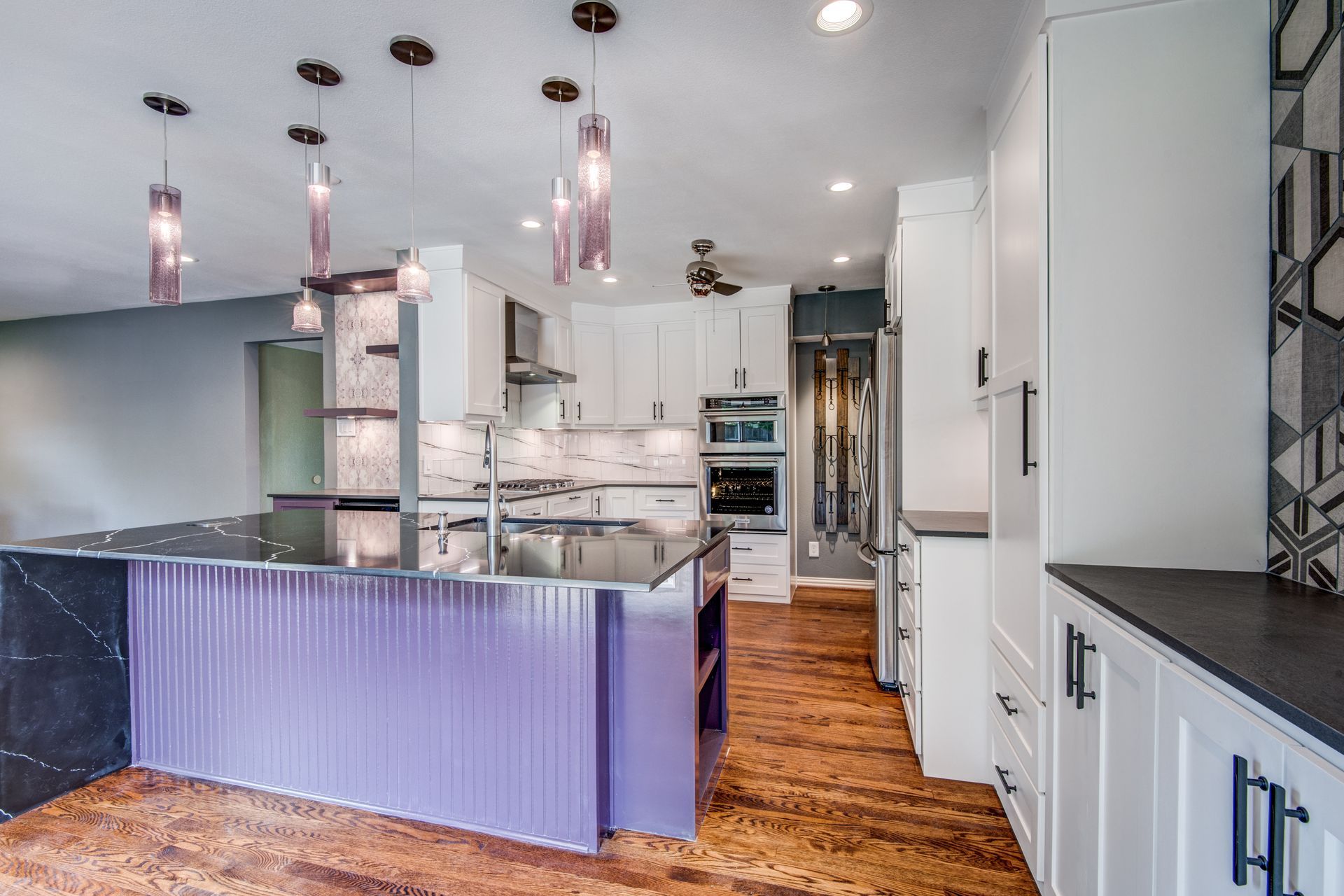 A kitchen with a purple island and white cabinets.