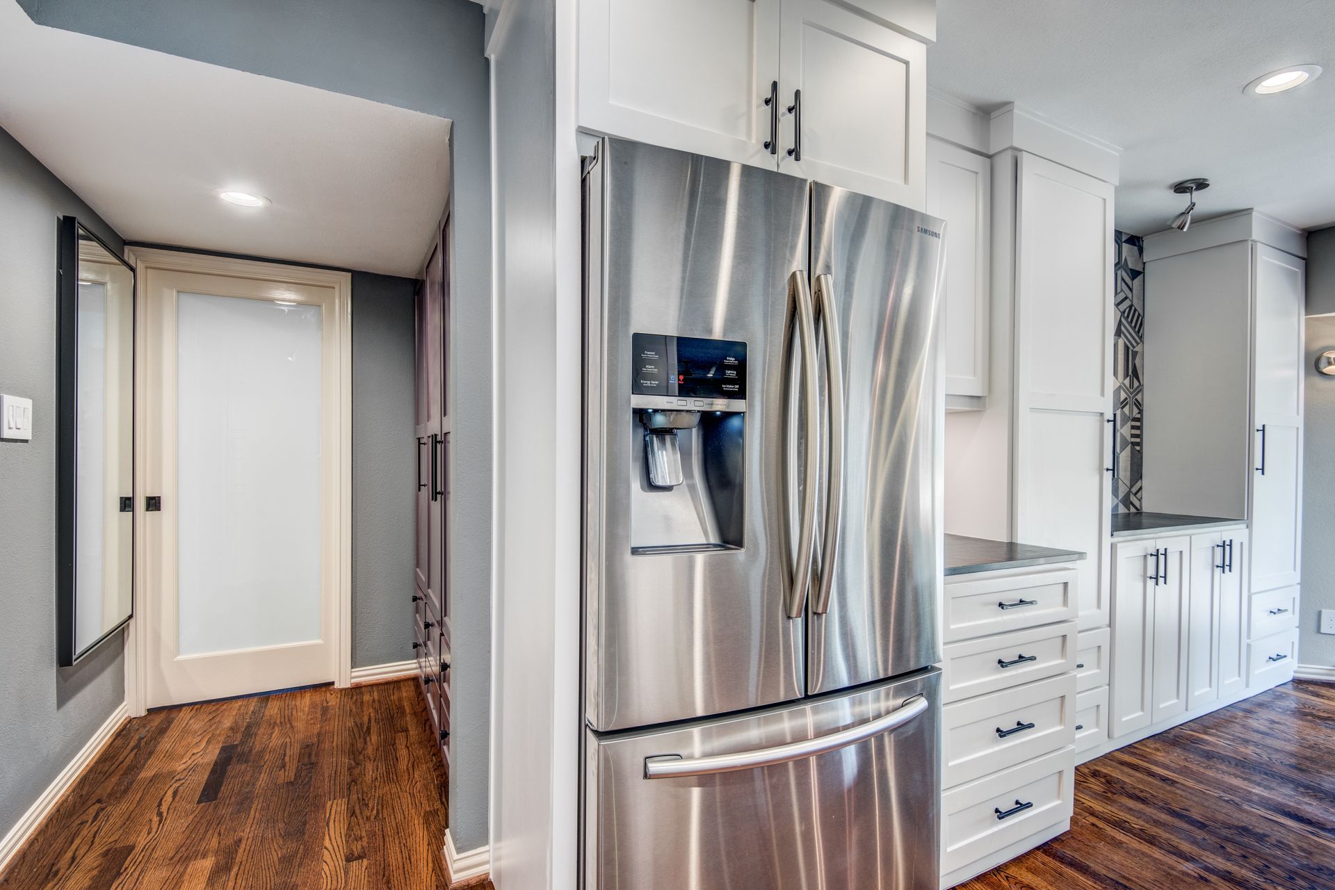 There is a stainless steel refrigerator in the middle of the kitchen.