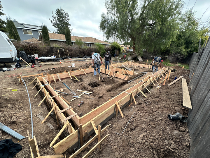 A group of construction workers are working on a house foundation.