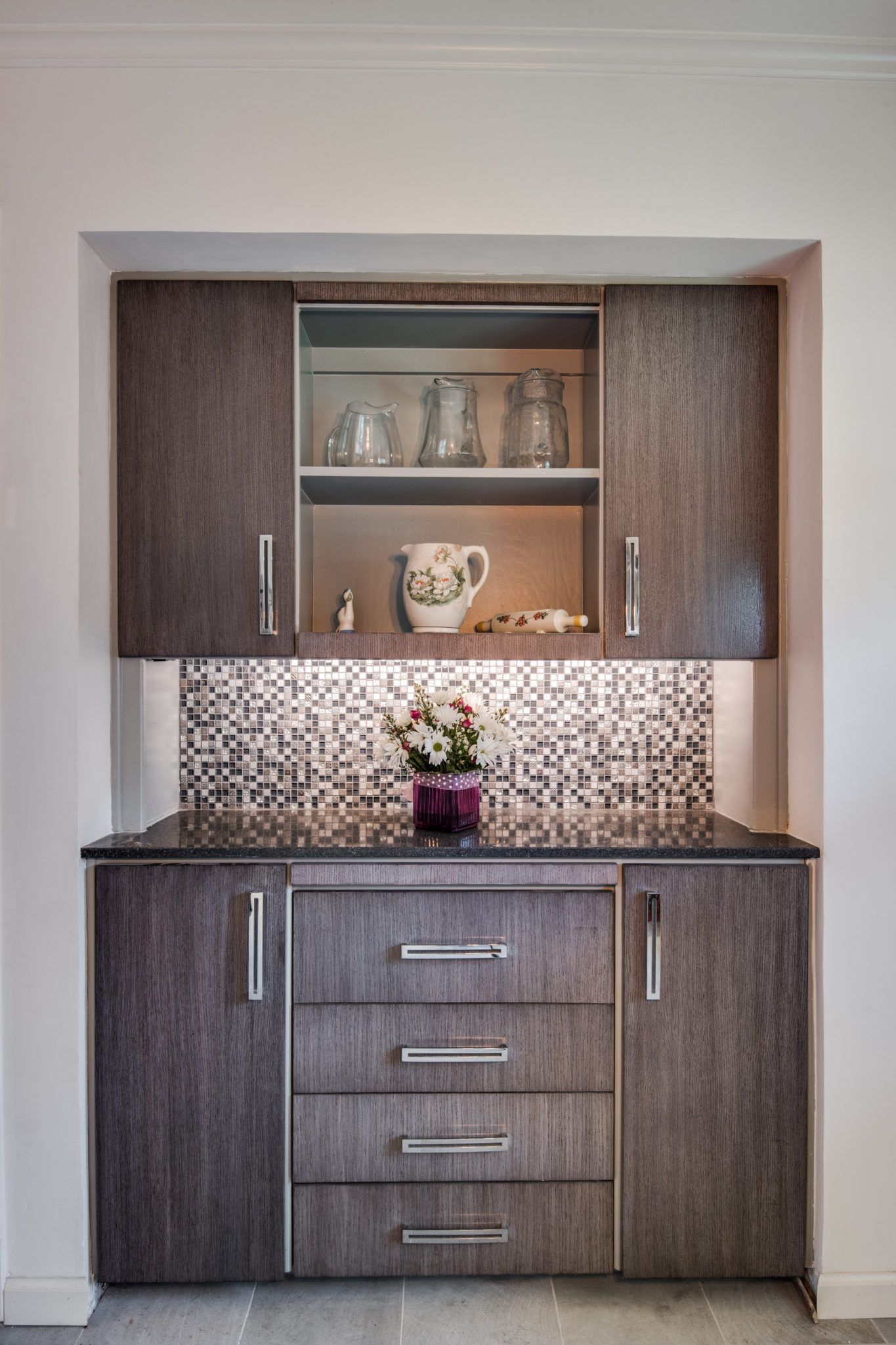 There is a vase of flowers in the middle of the cabinet.