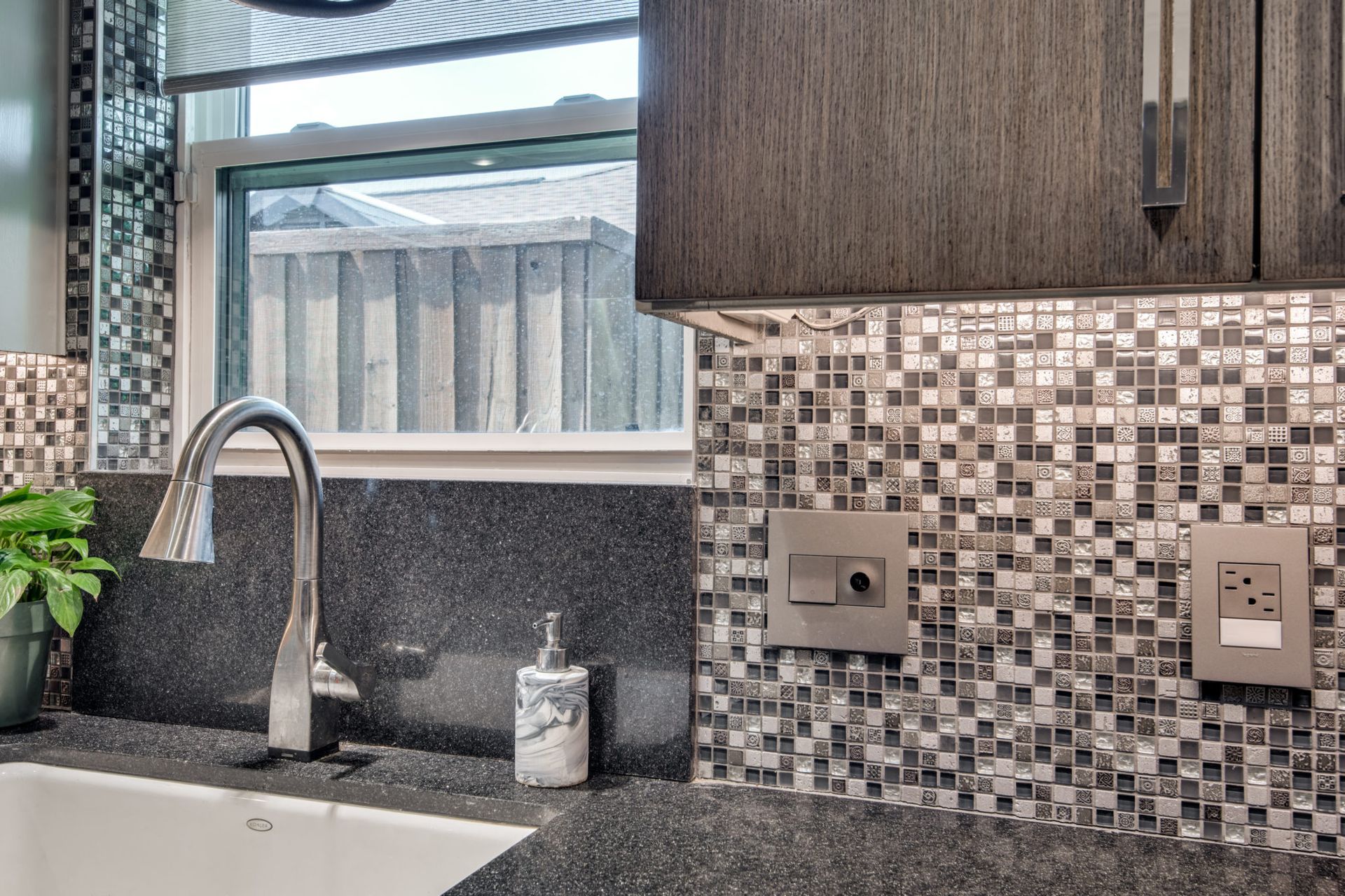 A kitchen sink with a soap dispenser and a window.