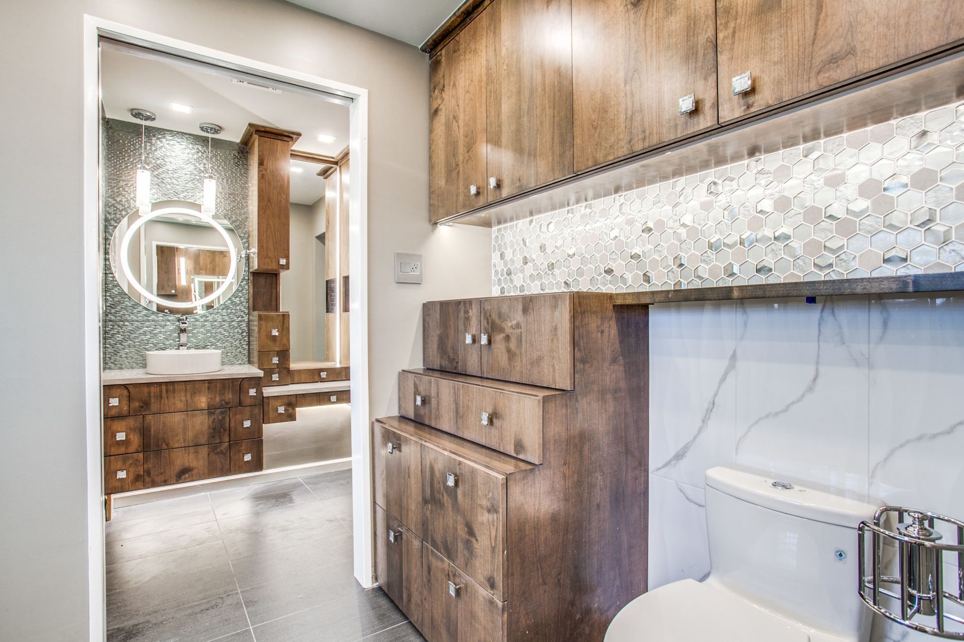 A bathroom with wooden cabinets , a toilet , a sink and a mirror.