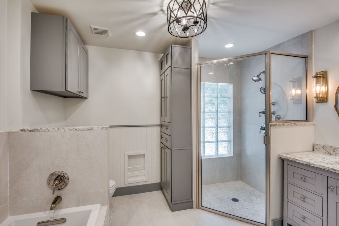 A bathroom with a walk in shower , sink , and cabinets.
