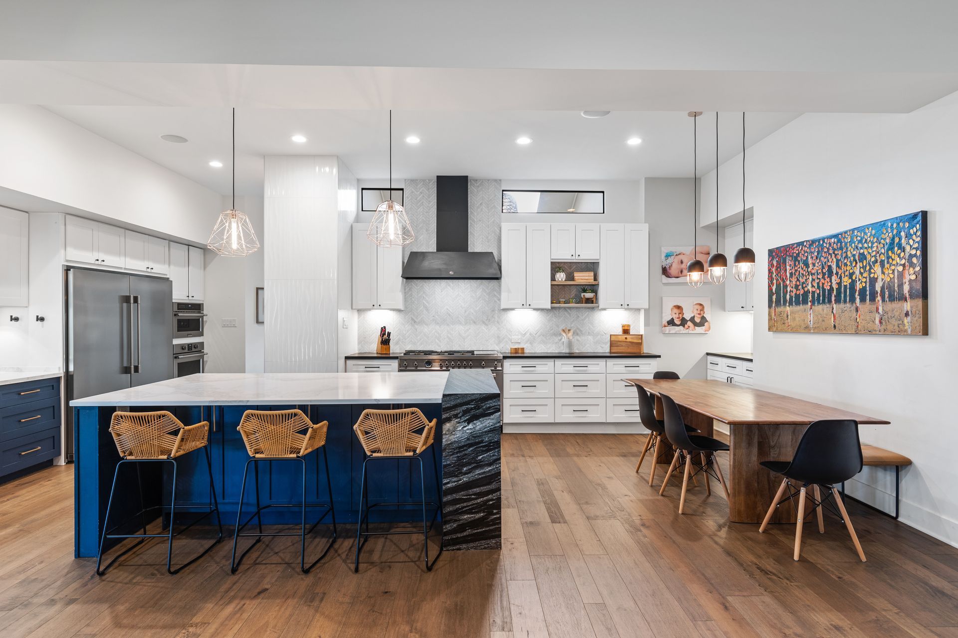 A kitchen with blue cabinets , white cabinets , a large island , a table and chairs.