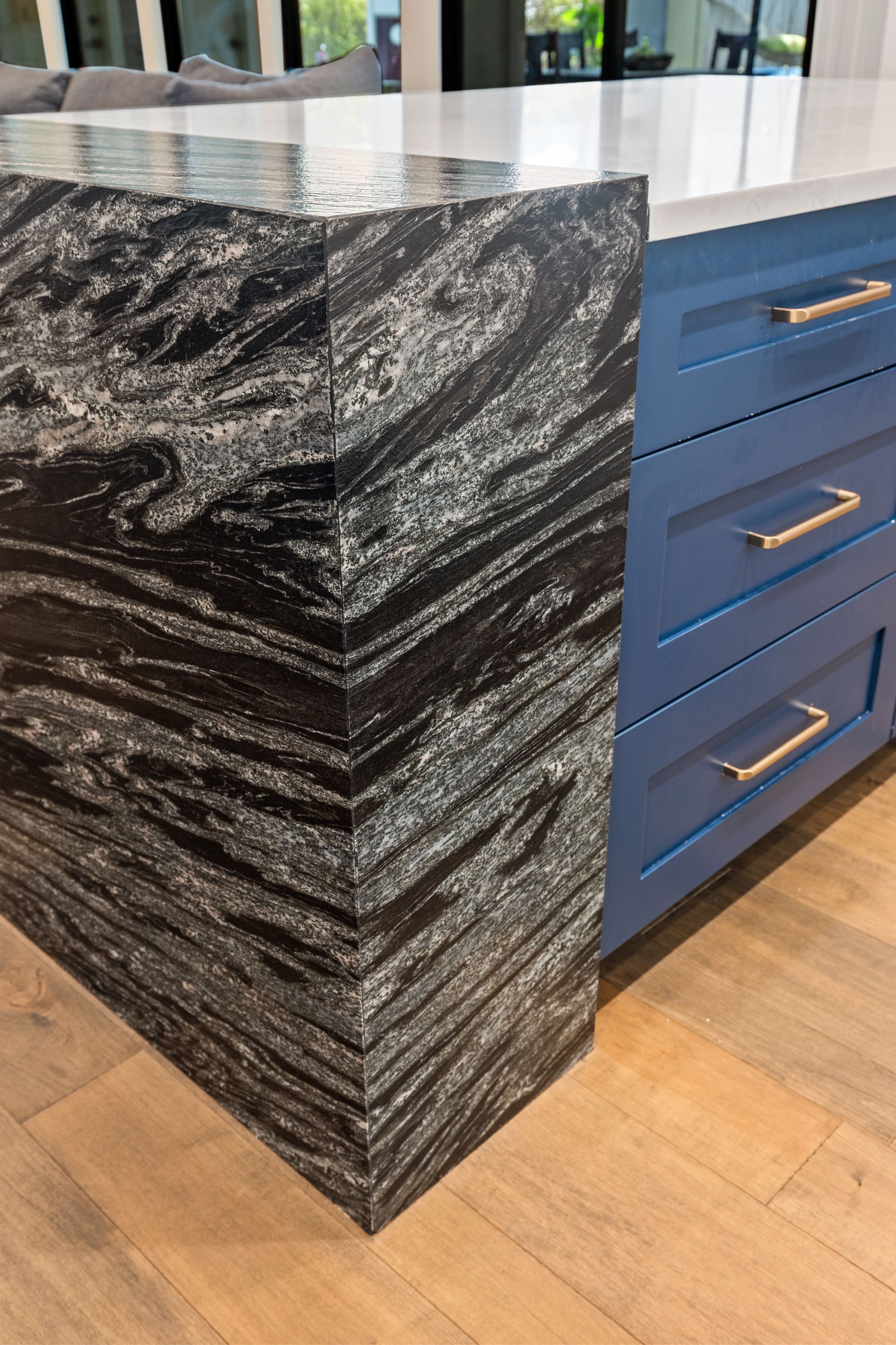A kitchen island with a granite counter top and blue cabinets.