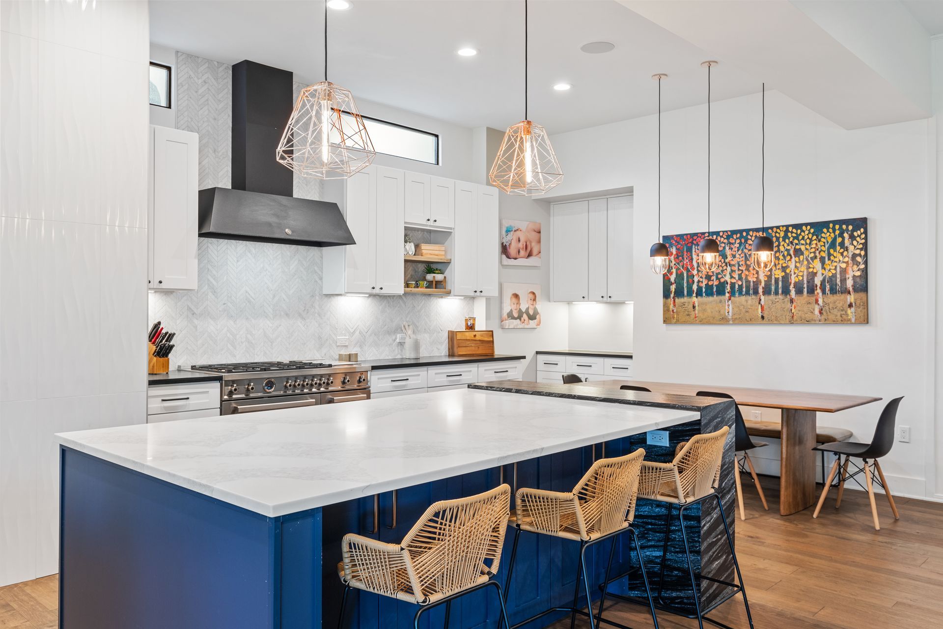 A kitchen with a blue island , white counter tops , and wicker chairs.