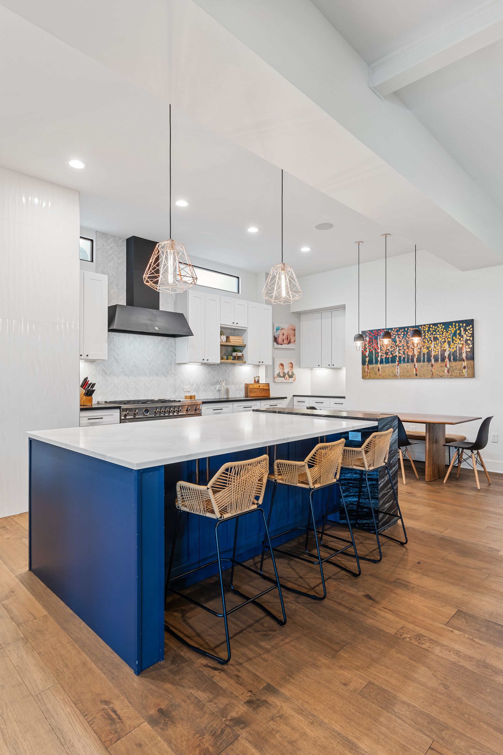 A kitchen with a blue island and wicker chairs.