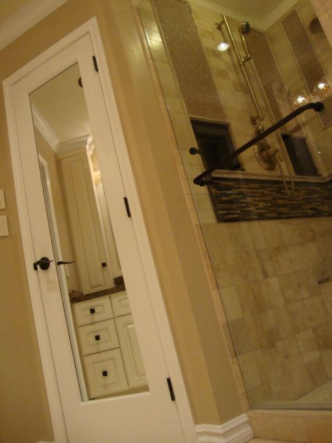 A bathroom with a walk in shower and a mirrored door