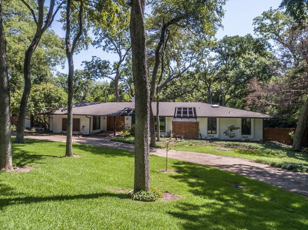 A house remodel  with a lot of grass and trees in front of it