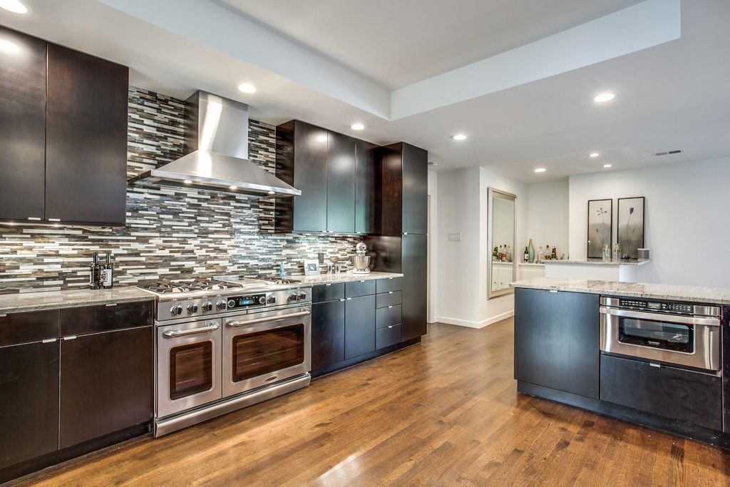 A kitchen with stainless steel appliances and wooden floors.