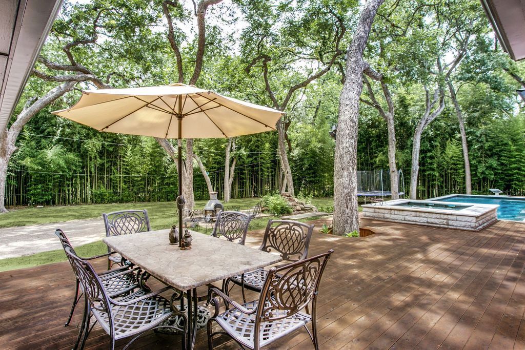 A patio with a table and chairs and an umbrella next to a pool.