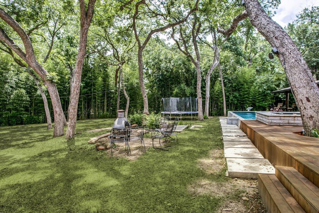 There is a fire pit in the middle of the backyard surrounded by trees.