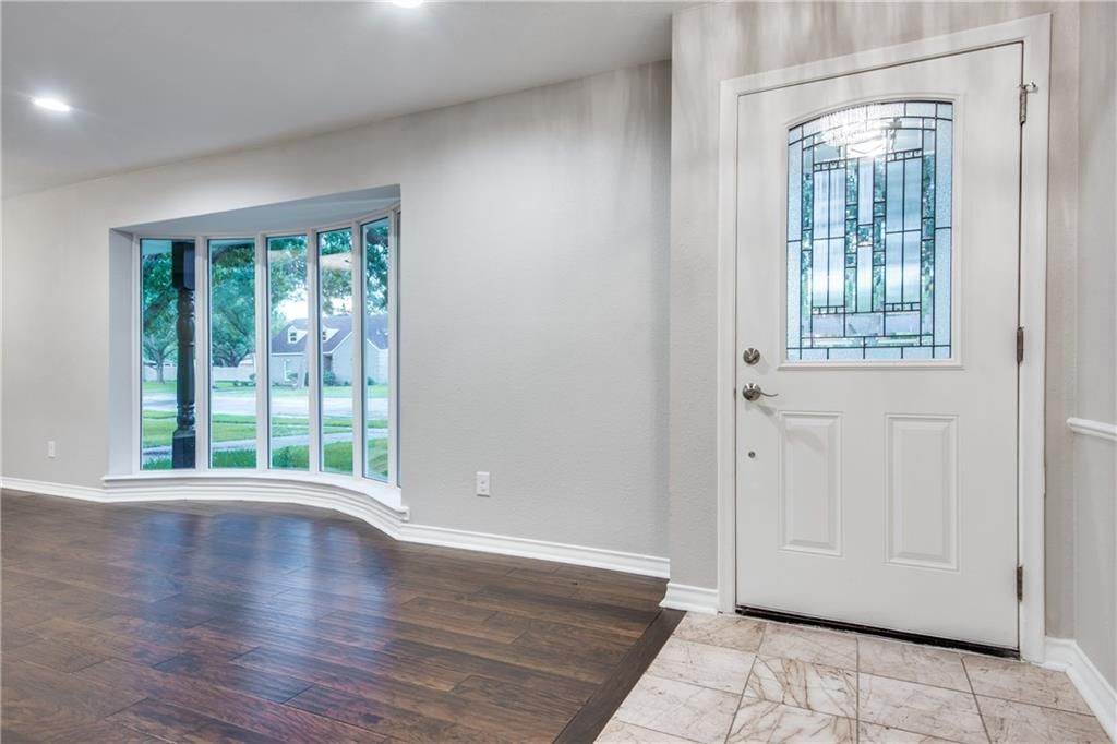 An empty room with a white door and a large window.