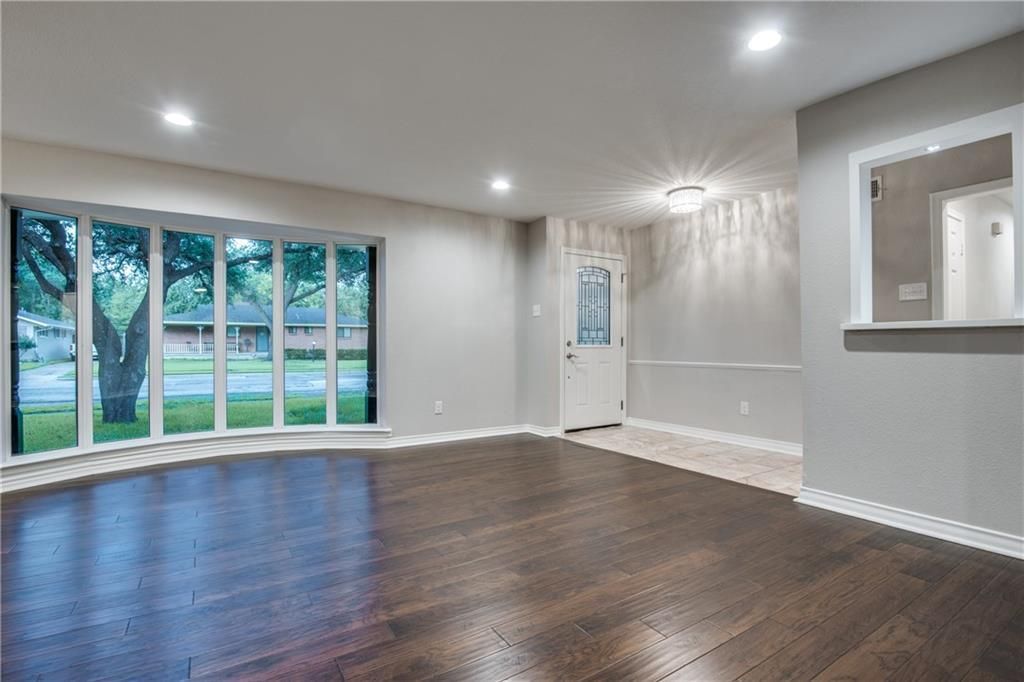 An empty living room with hardwood floors and lots of windows.
