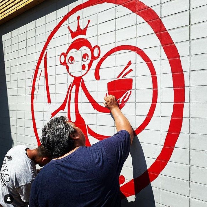 A man is painting a picture of a monkey on a wall