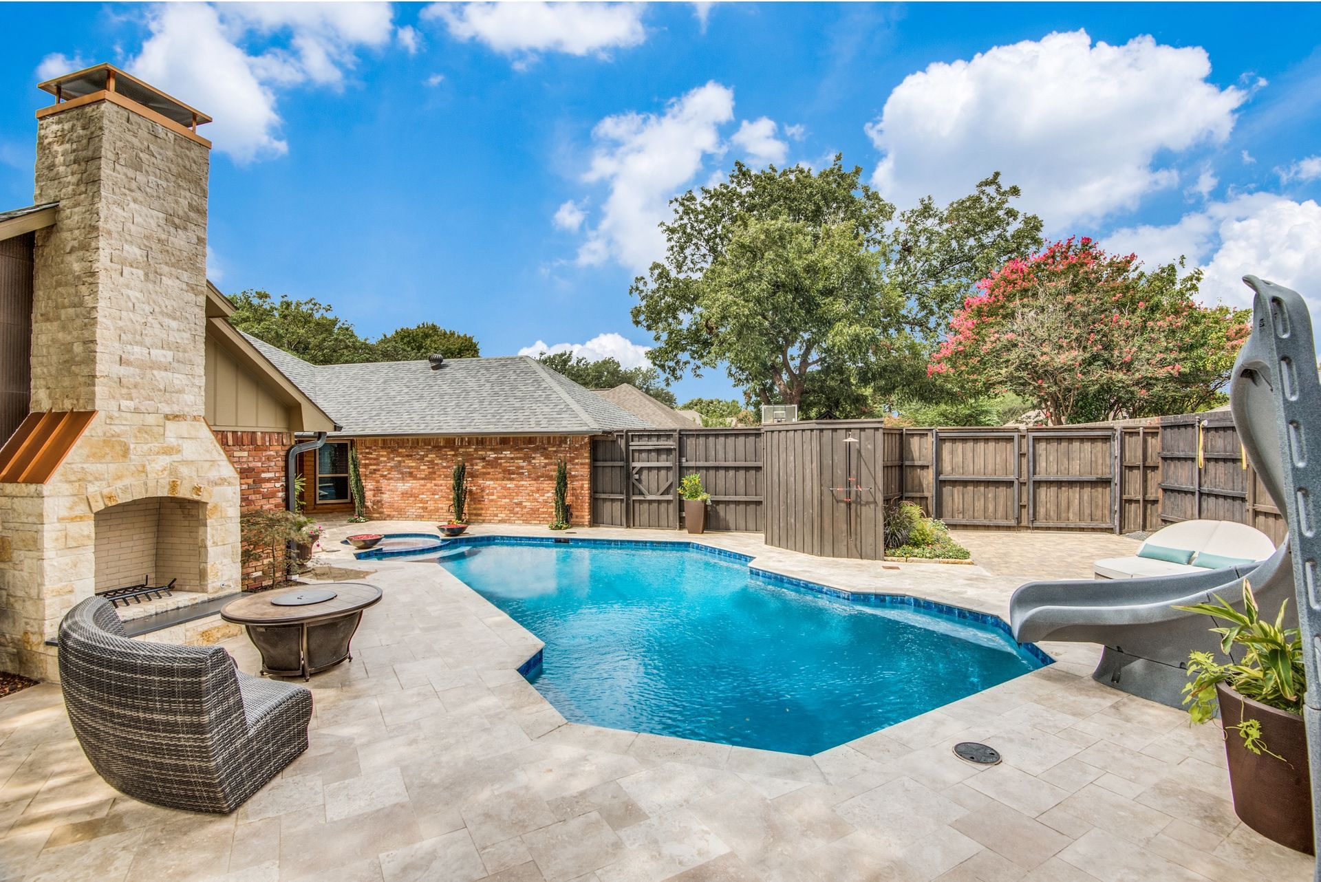 There is a large swimming pool in the backyard of a house.