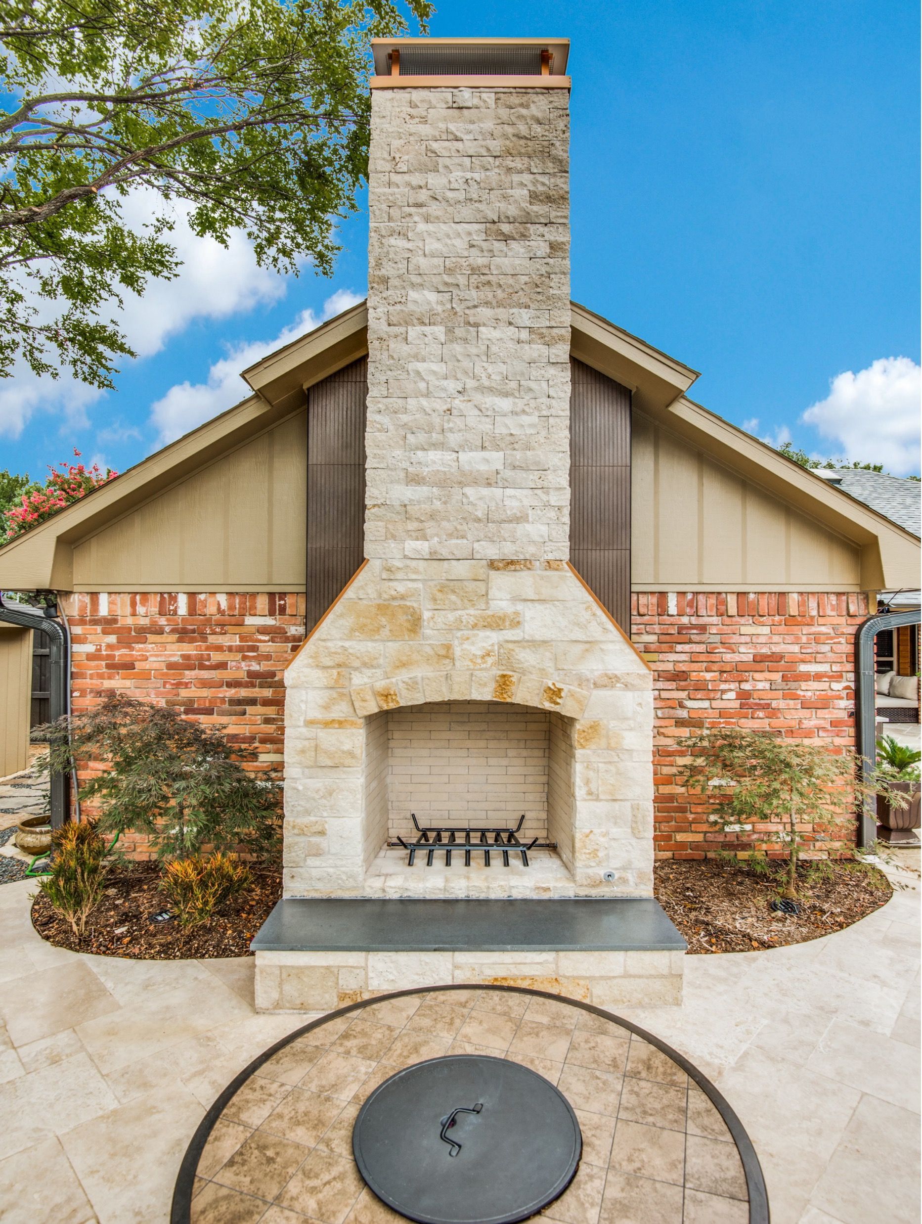 A large stone fireplace is in front of a brick house.