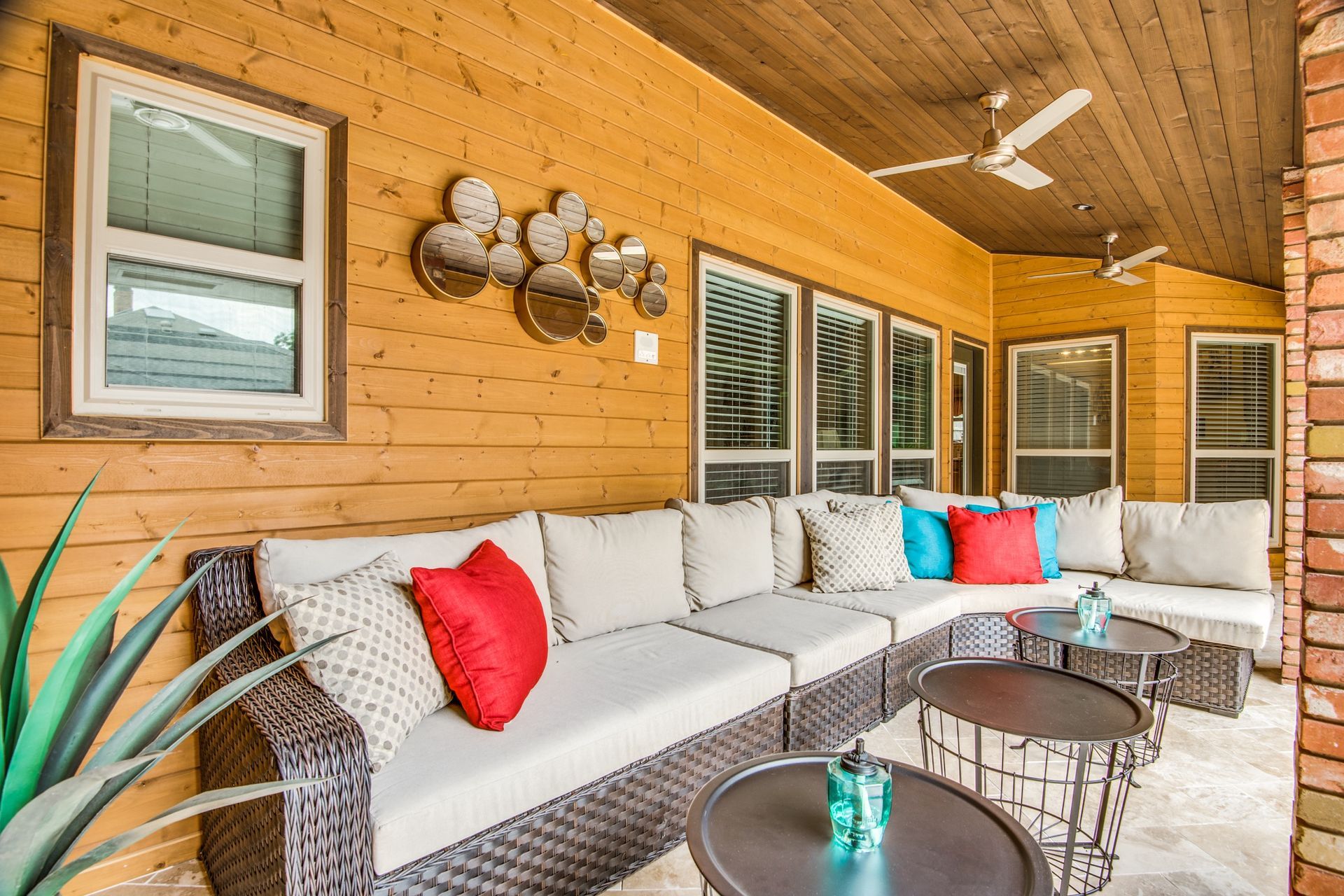 A porch with a couch , tables , and a ceiling fan.