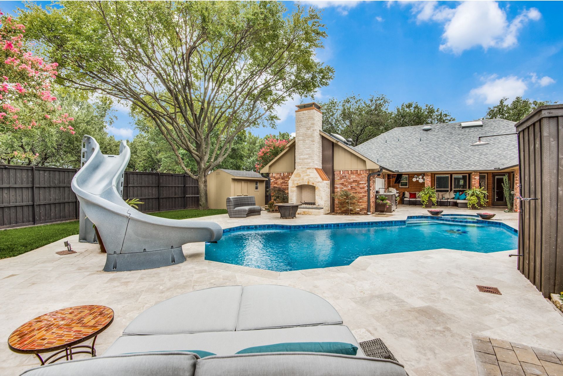 A large swimming pool with a slide in the backyard of a house.