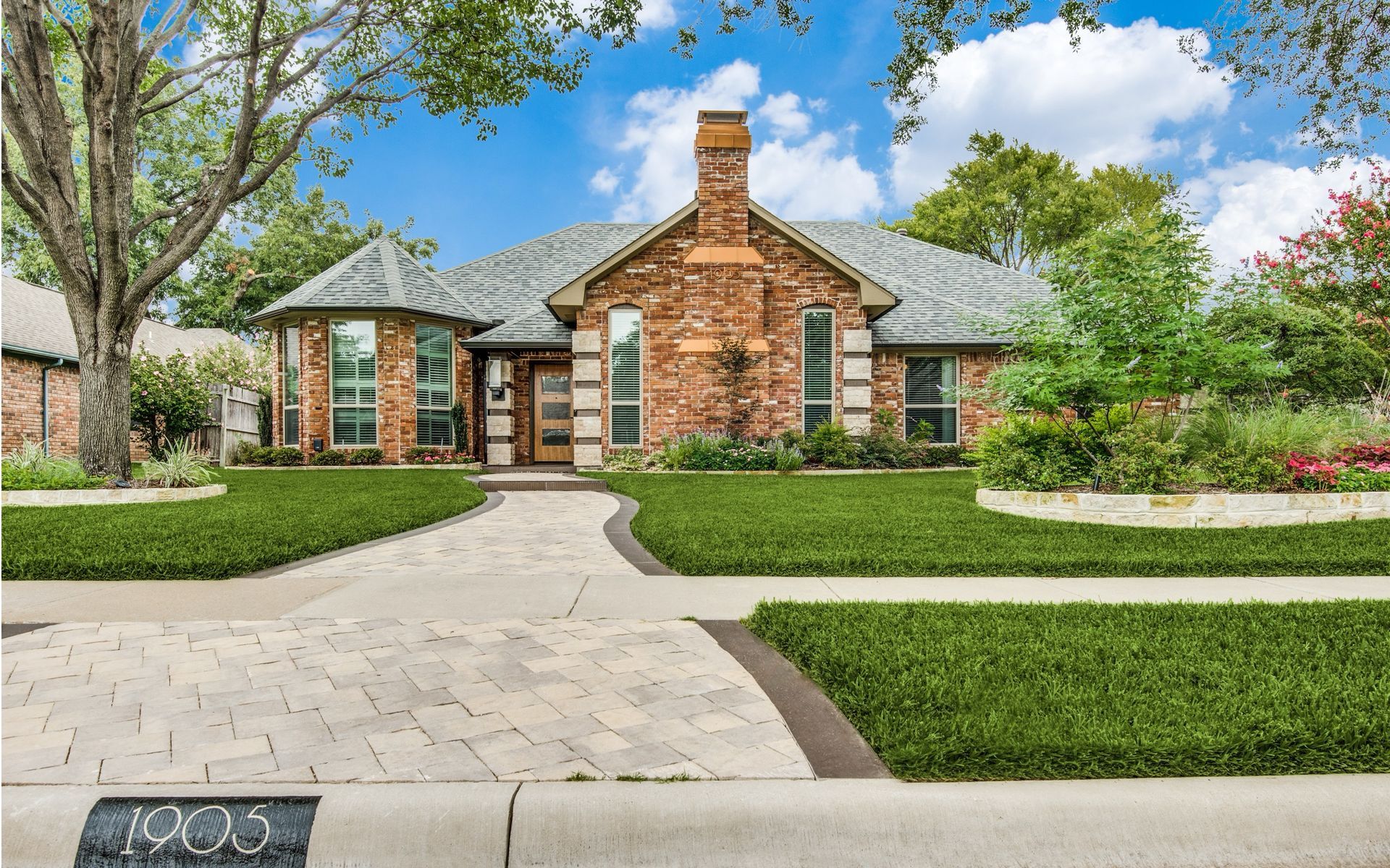 A large brick house with a lush green lawn in front of it.