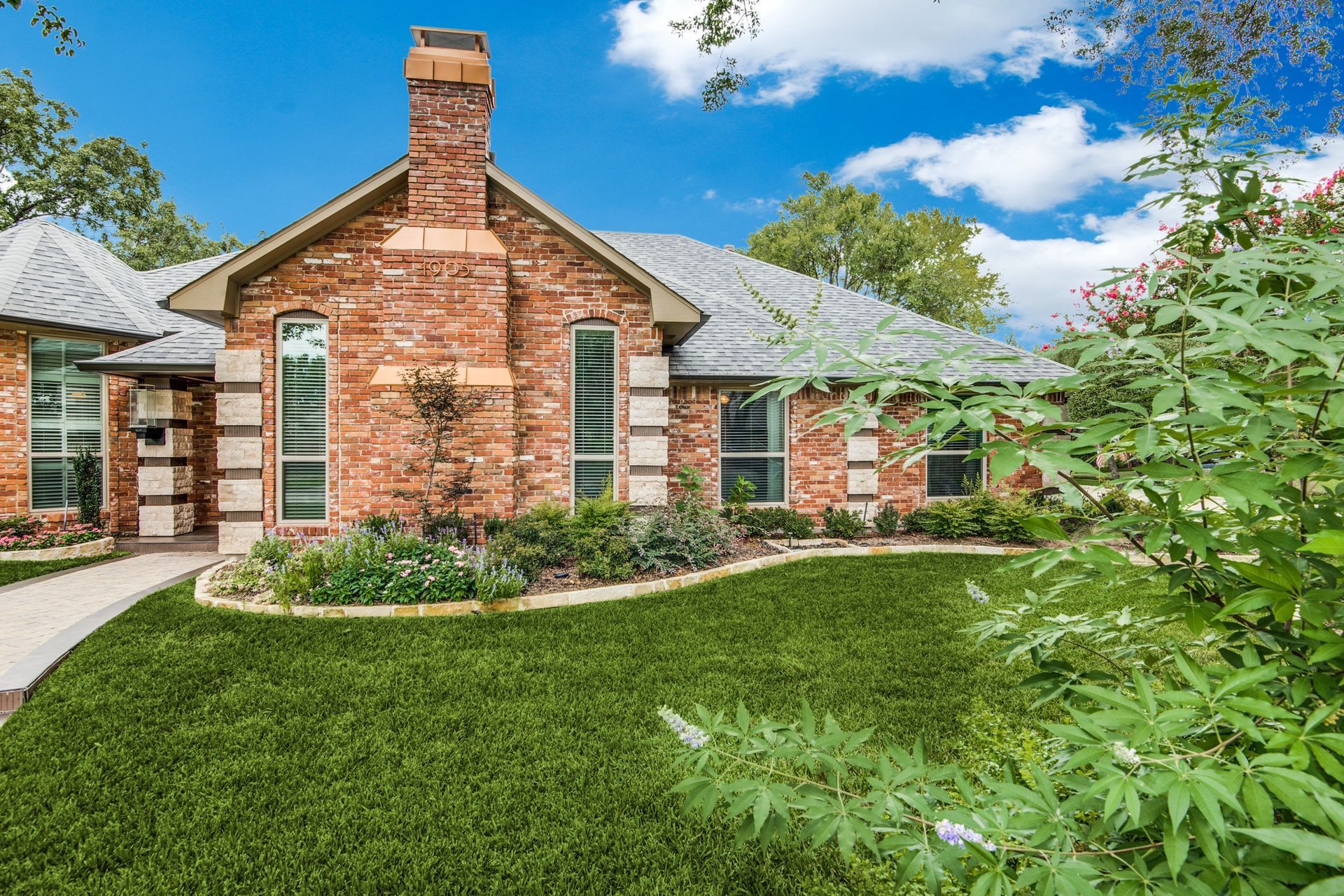 A brick house with a lush green lawn in front of it.