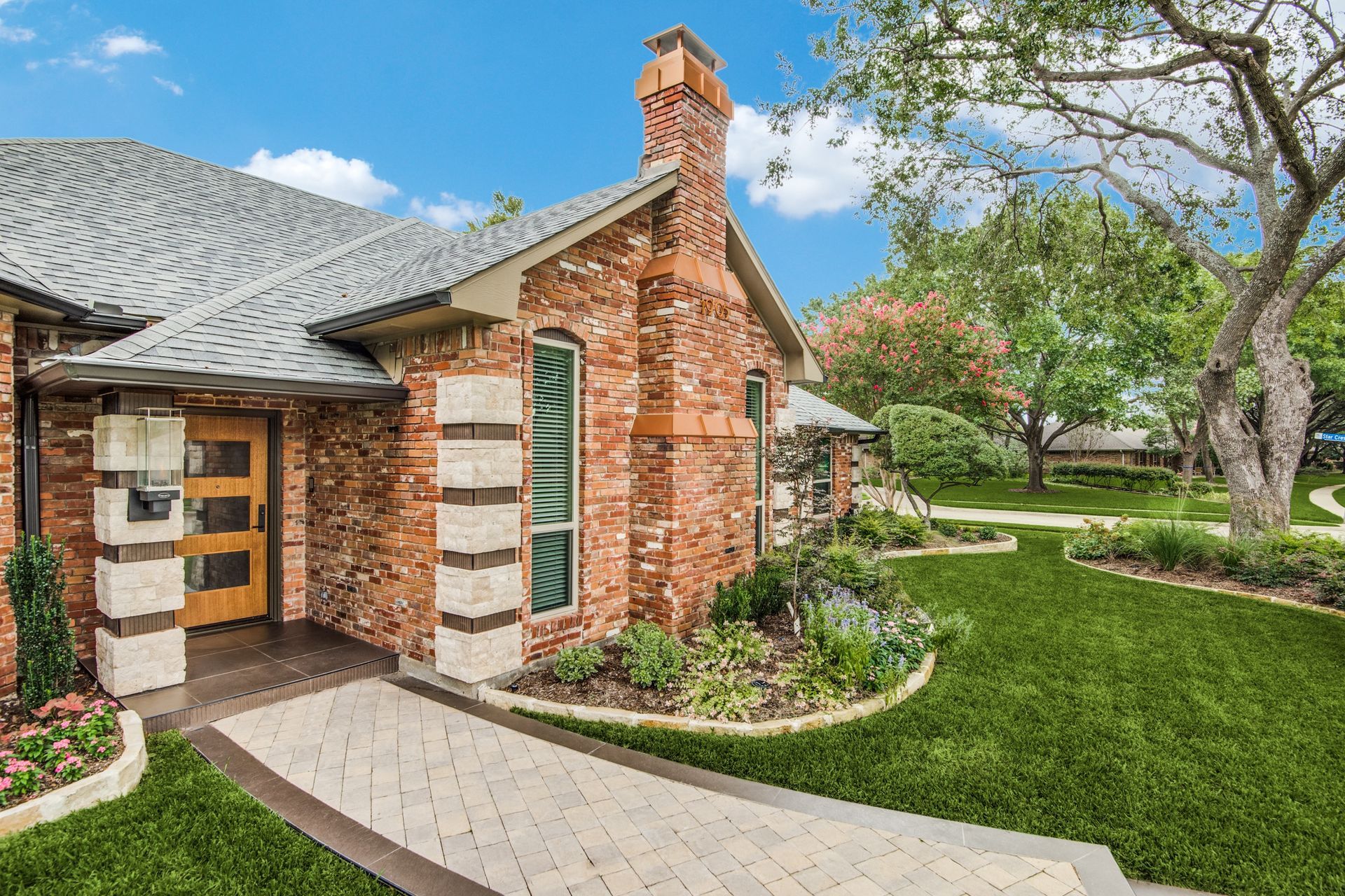 A brick house with a lush green lawn and a walkway leading to it.