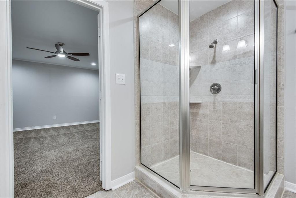 A bathroom with a walk in shower and a ceiling fan.