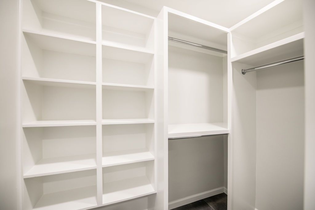 A walk in closet with lots of shelves and clothes racks.